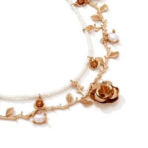 Detailed macro view of layered gold floral necklace with pearls and rose charms