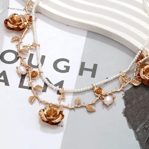 Close-up of double-layered gold necklace with rose pendant and white faux pearls