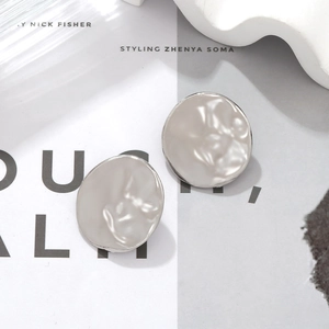 Macro detail of textured silver round earrings with hammer finish and relief pattern