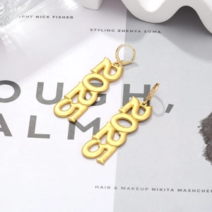 Detail of 2021 number earrings with gold finish and leverback hooks on a magazine