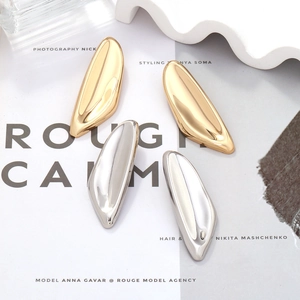 Close-up of irregular molten earrings in polished gold and silver on a fashion magazine