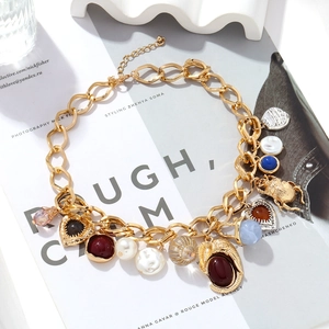 Makroaufnahme der goldenen Vintage-Kette mit Herz- und Käferanhängern sowie Perlen