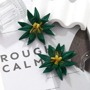 Close-up of handmade dark green beaded flower earrings with tiered petals and yellow center