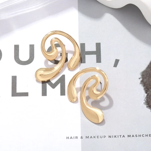 Vue rapprochée de boucles d'oreilles spirales dorées au design fluide et poli sur fond blanc