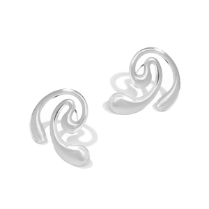 Détail macro de boucles d'oreilles spirales argentées au design ondulé poli moderne