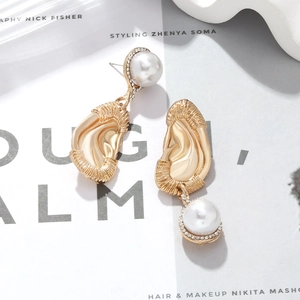 Creative gold ear-shaped earrings with faux pearls and rhinestones on fashion magazine