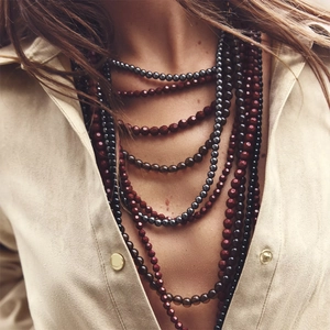 Multilayer beaded necklace with red and brown gradient beads on a suede shirt