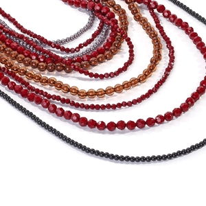 Macro detail of multilayer beads in red, amber, and pearl for cascading necklace