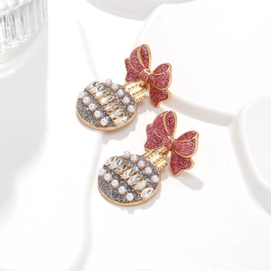 Dettaglio di orecchini natalizi con fiocco rosso e sfere glitterate con perle di cristallo
