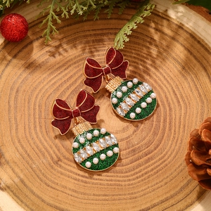 Dettaglio di orecchini a fiocco natalizi con glitter rossi, disco verde e perle