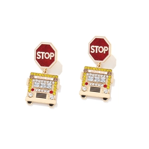 Macro detail of school bus earrings with colorful rhinestones and red stop sign