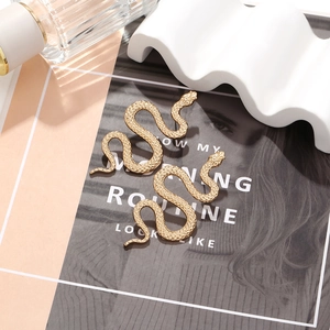 Macro detail of golden snake earring showing intricate scale texture and S-curve design
