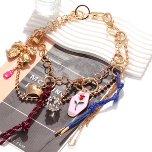 Detail of layered necklace featuring gold heart, pink enamel charms and mixed metal chains