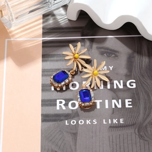 Detail of elegant daisy earrings with navy blue crystal pendant on a lifestyle backdrop