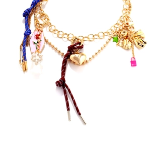 Close-up of layered necklace with heart, rose pendant, and colorful woven rope details
