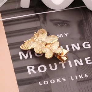 Pince à cheveux papillon dorée avec ailes en métal texturé et design minimaliste