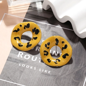 Detail of yellow enamel leopard print hoop earrings with a glossy geometric finish
