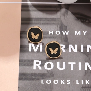 Detail of vintage irregular oval enamel studs with a gold butterfly motif on a magazine