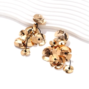 Detail of long handmade drop earrings with gold floral metal plates and black beaded cord