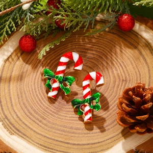 Close-up of Christmas candy cane earrings with green bows on a rustic wooden stand