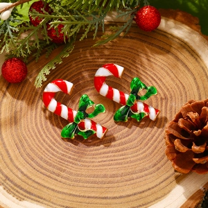 Christmas candy cane earrings with green bows on a festive wooden pine background