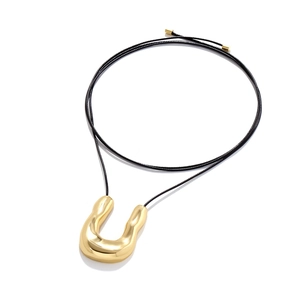 Minimalist gold U-shaped pendant on black cord necklace with organic fluid texture