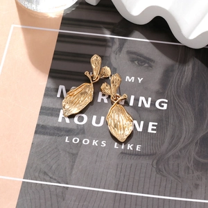 Textured gold leaf drop earrings with hammered metal finish on a fashion magazine