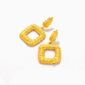 Close-up of vintage golden leaf texture on square geometric drop earrings in matte finish