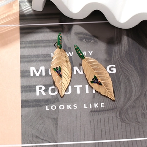 Golden alloy leaf earrings with green enamel accent and colorful insect patterns