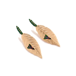 Macro detail of golden leaf earrings with green enamel dots and insect motif embellishment