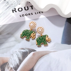 Detail of green enamel elephant drop earrings with faux pearls and golden floral texture