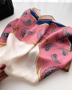 Detailed view of paisley silk scarf texture with gold buckle prints and pink accents