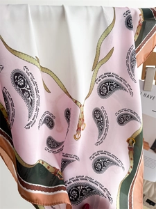 Detail of silk scarf with pink paisley print, decorative belt motifs and rope borders