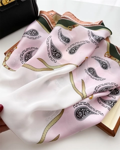 Detail of silk scarf with paisley patterns draped over a black leather bag