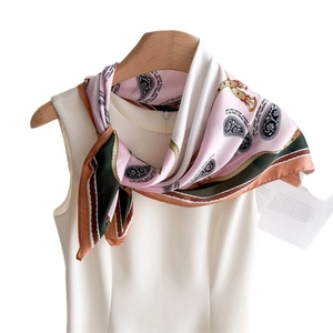 Pink silk scarf with paisley and gold chain patterns on a white dress with wooden hanger