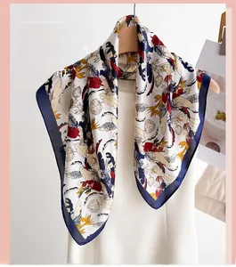 Close-up of tropical leaf print silk scarf hanging on a wooden hanger with white dress
