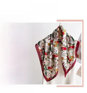 Close-up of floral print silk scarf with elegant red border and vibrant leaf patterns