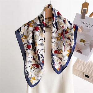 Elegant tropical floral print silk scarf with navy border draped on a white dress