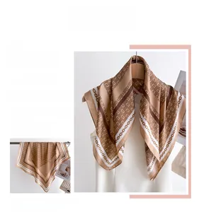 Detailed view of silk scarf with classic gold chain print and geometric logo patterns