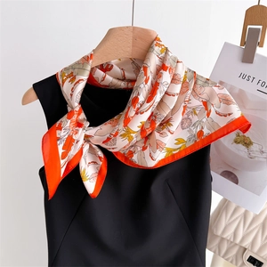 Detail of silk square scarf with tropical leaf print and orange rolled edges on a hanger