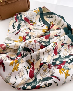 Close-up of tropical leaf print silk scarf with deep green borders and smooth texture