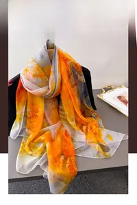 Detailed view of long lightweight silk scarf with orange and grey abstract ink print