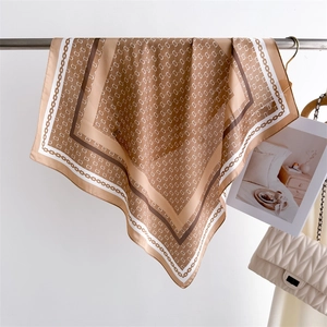 Detailed view of square silk scarf with brown geometric patterns and golden chain borders