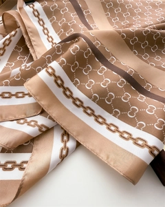 Macro detail of classic chain and logo print on silky satin square scarf fabric