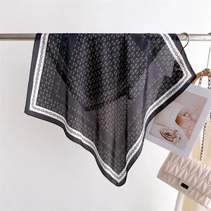 Detail of elegant black and white silk square scarf with geometric chain prints on a hanger