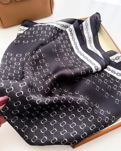 Close-up of silk scarf with black and white geometric chain patterns and silky texture