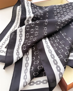 Close-up of silk square scarf with classic black and white chain and interlocked pattern