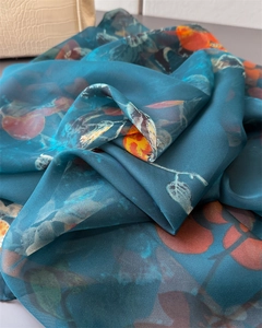 Detail of teal gauze scarf with vibrant orange floral print and soft draped texture