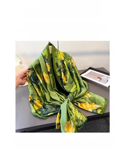 Macro detail of lightweight faux silk scarf with yellow lotus print on vibrant green fabric