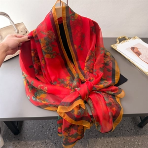 Elegant red silk shawl with floral pattern and striped edges displayed with accessories
